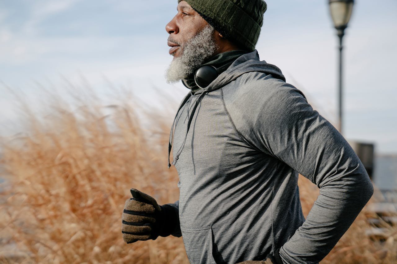 Senior African American man enjoying a run outdoors in warm autumn clothing.
