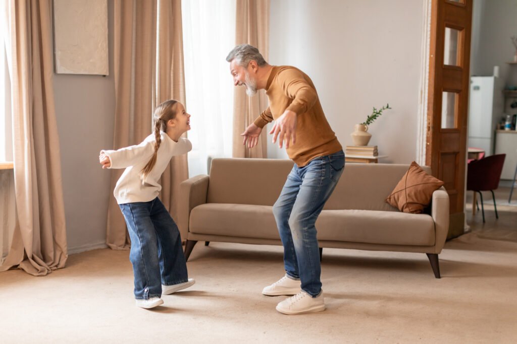 grandfather engaging in a playful dance with young granddaughter